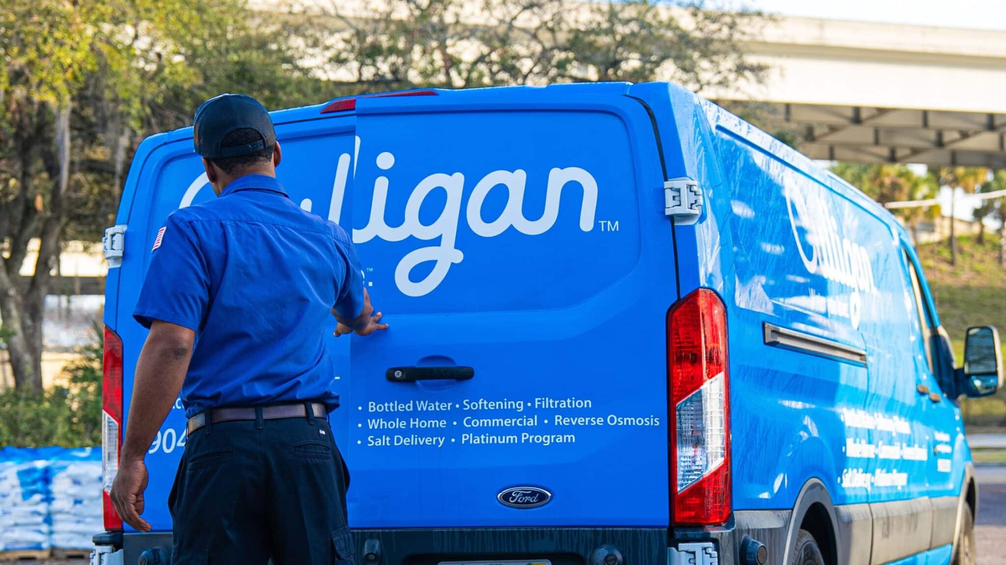 Water technician in a Culligan-branded van arriving at a residential address.